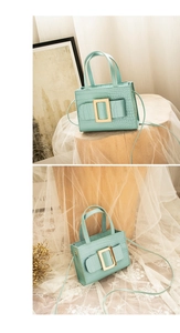 Detail of mint green crocodile pattern handbag with gold square buckle and dual handles