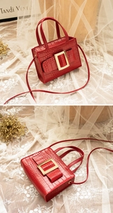Detail of red crocodile textured PU leather bag featuring a bold golden square buckle