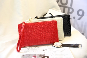 Trois pochettes à motif crocodile en rouge, blanc et noir avec dragonnes amovibles