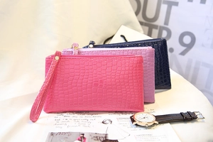 Détail de pochettes à motif crocodile en rose, violet et bleu avec dragonne de poignet