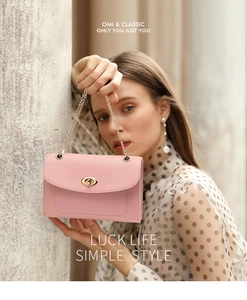 Sac bandoulière rose avec chaîne dorée et cuir texturé porté par un modèle