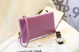 Détail d'une pochette violette texture crocodile avec fermeture éclair dorée