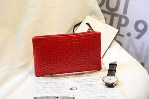 Vue détaillée du porte-monnaie rouge à motif crocodile sur fond de magazine chic
