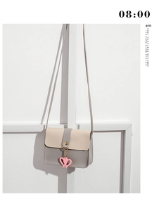 Detail shot of a two-tone PU leather crossbody bag featuring a pink double heart charm