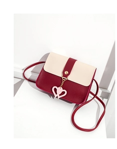 Detail of minimalist contrast-color crossbody bag with pink heart pendant and gold buckle