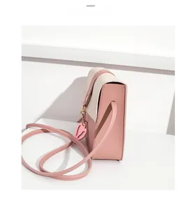 Detail view of pink and beige patchwork phone bag with heart pendant and PU texture