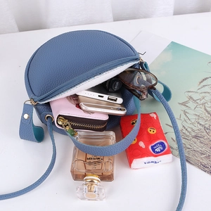 Blue round crossbody bag with litchi texture showing interior capacity and zipper