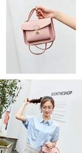 Detail of pink lychee leather handbag with gold clasp shown in hand and crossbody