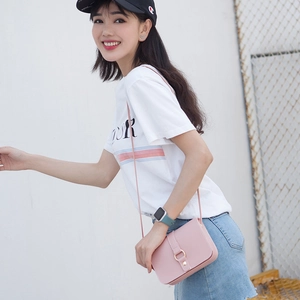 Pink minimalist crossbody square bag with gold ring buckle worn by a model outdoors