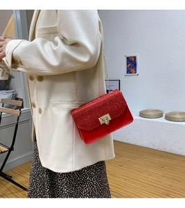 Detailed view of red sequin crossbody bag featuring a gold metal chain strap and push lock