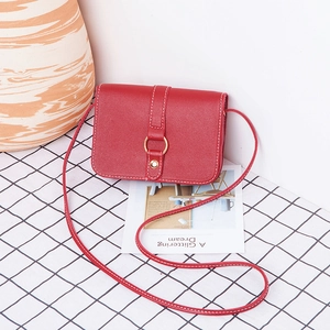 Modern red leather crossbody square bag with metal ring buckle on checkered background