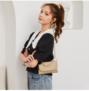 Détail d'un sac bandoulière beige en cuir PU avec chaîne acrylique et sangle dorée