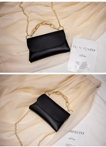 Détail du sac bandoulière en cuir noir avec chaîne en résine et sangle métal
