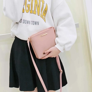 Bolso tipo cubo rosa claro con logotipo metálico y correa ajustable para mujer