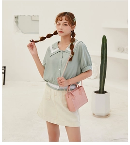 Close-up of a pink crocodile pattern handbag held by a model in a pastel outfit