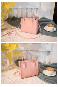 Detailed close-up of light pink croc-embossed small square handbag with double handles