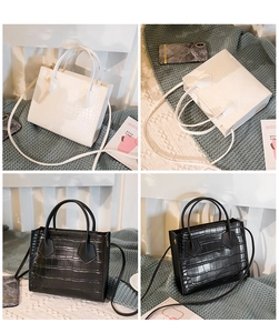 Detailed view of crocodile pattern texture on black and white square handbags