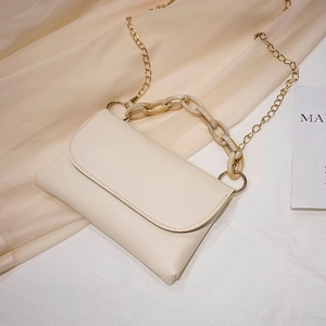 Sac à bandoulière beige chic avec poignée en chaîne acrylique sur fond de soie