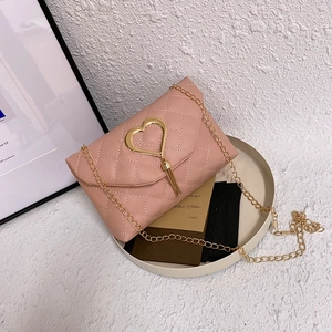 Elegant pink quilted crossbody bag with heart pendant and gold chain strap