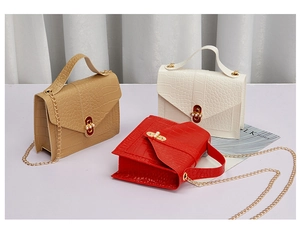 Detail view of crocodile pattern chain bags in beige, brown, and red with pearl clasps