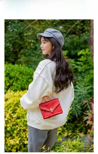Detailed view of red crocodile pattern crossbody bag with golden twist lock on a model