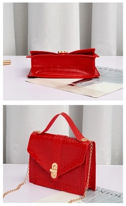 Detail of red crocodile pattern handbag with gold chain strap and pearl buckle clasp