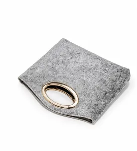 Detail of grey felt handbag featuring elegant gold oval metal handle and fuzzy texture