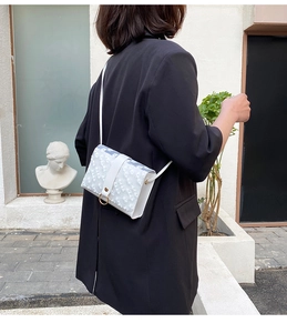 Detail of white daisy lace crossbody bag with gold ring on a female model