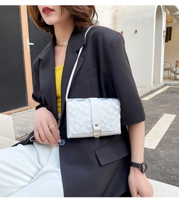 Detailed embroidery of white daisy lace and gold ring hardware on women's shoulder bag