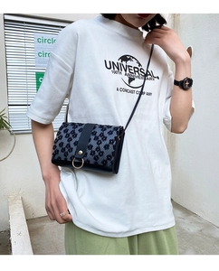 Street style shot of a daisy pattern flap crossbody bag with a golden ring buckle