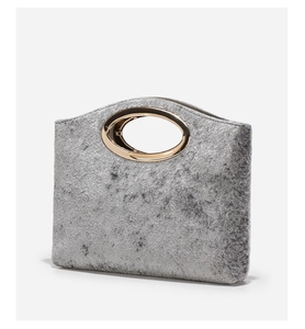 Detail of silver gray textured handbag featuring elegant oval gold metal handle