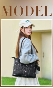 Close-up of black quilted tote bag with floral embroidery and mini pouch charm detail
