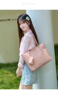 Outdoor shot of a pink woven tote bag with a matching small hanging coin purse accessory
