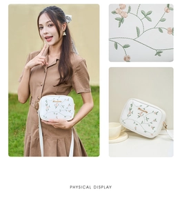 Macro detail of floral embroidery and gold Smiley logo on a white crossbody camera bag