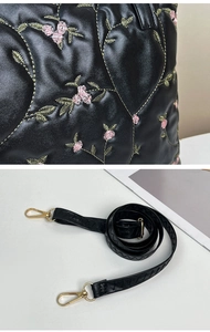 Detail of heart quilting and flower embroidery on black tote with golden hardware