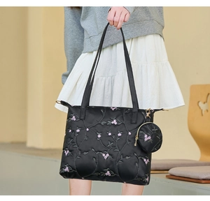 Detail of black quilted tote bag with floral embroidery and matching round coin purse