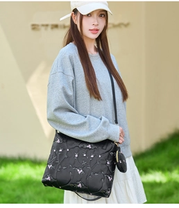 Detail of black tote bag with pink floral embroidery and round coin purse attachment