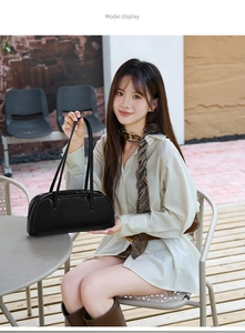 Detailansicht einer schwarzen matten Baguette-Tasche aus Leder, getragen von einem Model