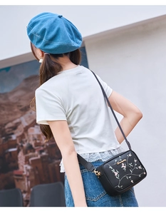 Close-up of black leather crossbody bag featuring exquisite pink floral embroidery detail