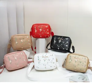 Multiple colorful crossbody bags with floral embroidery displayed on geometric stands