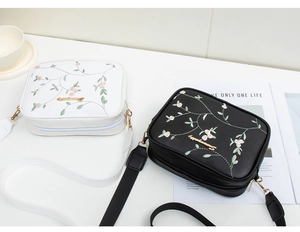 Close-up of floral embroidery detail on the PU leather camera bag with a wide strap