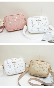 Detailed embroidery of pink flowers and leaves on a stylish rectangular camera bag strap