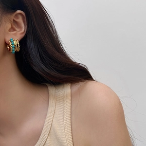 Détail rapproché de boucles d'oreilles bohèmes dorées avec perles turquoise sur mannequin