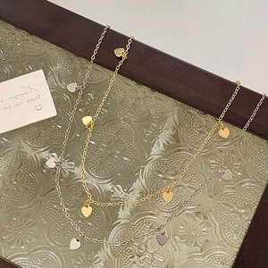 Detailansicht eleganter goldener und silberner Herzanhänger-Halsketten auf Glas