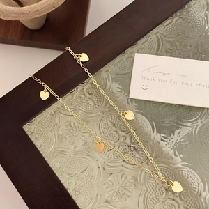 Nahaufnahme einer goldenen Herzanhänger-Halskette auf Vintage-Glas und Holzrahmen