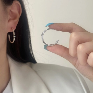 Silver C-shaped hoop earrings with black star zircon detail shown on a model