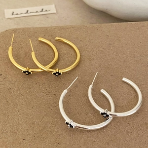 Elegant gold and silver hoop earrings with black clover design on handmade card