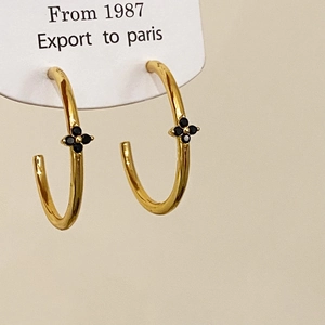 Detail of vintage gold C-shape earrings with black four-leaf clover zircon inlay