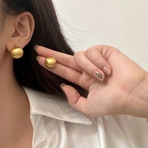 Boucles d'oreilles minimalistes en forme de haricot doré au fini mat sur le mannequin