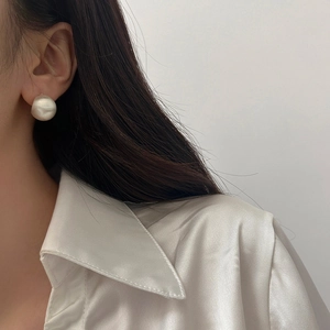 Gros plan d'un mannequin portant de grandes boucles d'oreilles boules argentées